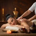 woman is putting massage bed with candle middle